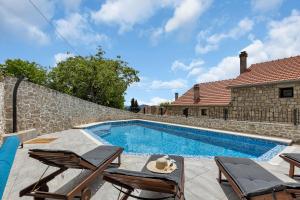 a swimming pool with chairs and a house at Holiday Home Sonja - Makarska Exklusiv in Vrgorac