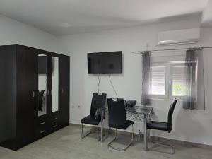 a room with a table and chairs and a television at SunSea Studio Apartment in Ðenovići