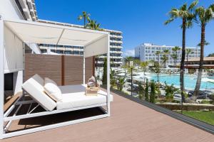 a porch with a white swing and a swimming pool at INNSiDE by Meliá Alcudia in Port d'Alcudia