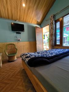 una camera da letto con un letto e una TV a schermo piatto di Lee Garden Himalayan Wooden Cottages a Kasol