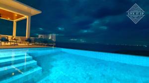 ein Schwimmbad in der Nacht mit dem Ozean im Hintergrund in der Unterkunft Santi Pura Villas in Ban Bang Po