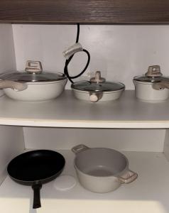 tres ollas y sartenes en un estante de una cocina en Solace Haven, en Manila