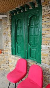 two pink chairs sitting in front of a green door at Shree Guru Home Stay in Jāmb +1 photo