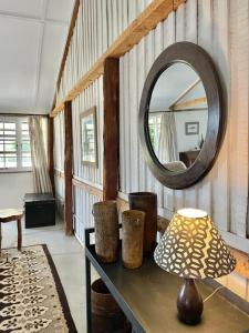 The Barn by YourHost Nanyuki Kenya في نانيوكي: طاولة مع مصباح ومرآة في الغرفة