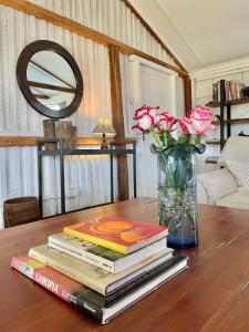 The Barn by YourHost Nanyuki Kenya في نانيوكي: كومة من الكتب على طاولة مع الزهور في مزهرية