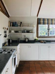 The Barn by YourHost Nanyuki Kenya في نانيوكي: مطبخ مع خزائن بيضاء وقمم منضدة سوداء +27 صورة