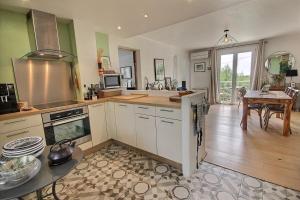 a kitchen with white cabinets and a dining room with a table at Cassis Centre, proximité port, plages et calanques in Cassis +6 photos