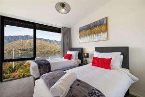 two beds in a room with a large window at Lakevista Retreat - Hot Tub - Spa Pool in Queenstown