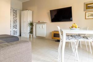 een woonkamer met een tafel en een tv aan de muur bij Estate By Case al Lago in Desenzano del Garda