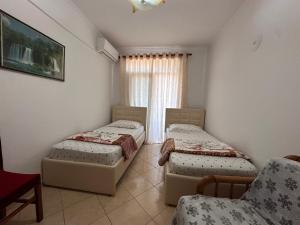 a room with two beds and a chair and a window at Anita Apartment in Përmet