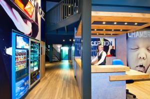 a man standing at a bar in a room with a tv at ibis budget Marne la Vallée Bry sur Marne in Bry-sur-Marne