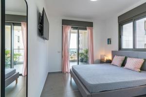 a bedroom with a bed and a tv and windows at Modern Comfort Escape by Sea N' Rent in Nahariyya
