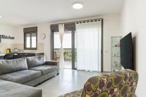 a living room with a couch and a kitchen at Modern Comfort Escape by Sea N' Rent in Nahariyya