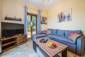 Una sala de estar con un sofá azul y un televisor en Villa Erato Klio, en Kiriánna 16 fotos más