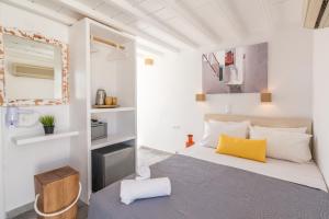 a small bedroom with a bed and a yellow pillow at Orpheas Rooms in Mikonos
