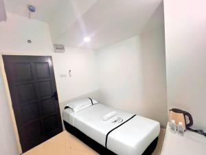 a small room with a bed and a black door at Seeds Hotel Premier Chow Kit Kuala Lumpur in Kuala Lumpur