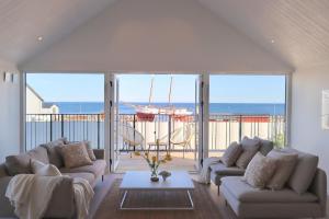 a living room with couches and a view of the ocean at Penthouse over the harbour in Skillinge