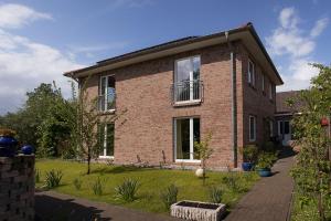 ein Backsteinhaus mit einem Rasenhof davor in der Unterkunft Familie Schwantes in Buxtehude