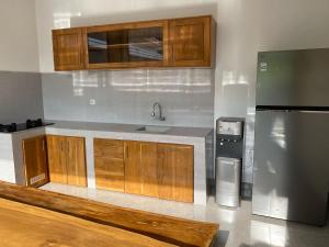a kitchen with wooden cabinets and a stainless steel refrigerator at Alit Guest House in Uluwatu