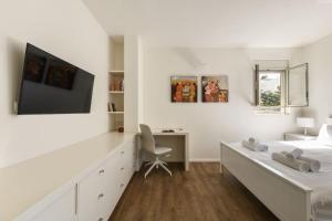Chic 2BR Apt w Large Windows in Tel Aviv Old North في تل أبيب: غرفة نوم بيضاء بسريرين ومكتب