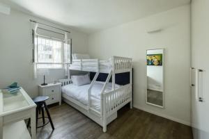 Chic 2BR Apt w Large Windows in Tel Aviv Old North في تل أبيب: غرفة نوم مع سريرين بطابقين ومكتب +26 صورة