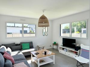 a living room with a couch and a tv at La baie, maison neuve proche des plagesMaison neuve, proche des plages, Mousterlin in Fouesnant