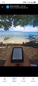 a tablet sitting on a bench in front of a beach at Bunaken Coral Homestay in Bunaken