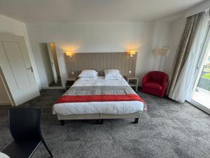 a hotel room with a bed and a red chair at Grand studio sur le golf de Chiberta in Anglet