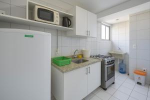 a white kitchen with a sink and a microwave at Apartamentos Verano in Natal