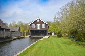 ホーニングにあるThe Boat House - Holiday Home in Horning on the Norfolk Broadsの川沿いに建つ庭付きの家