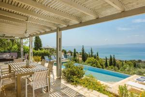 eine Terrasse mit Tisch und Stühlen und ein Swimmingpool in der Unterkunft Mounda Beach Villa in Ratzaklíon