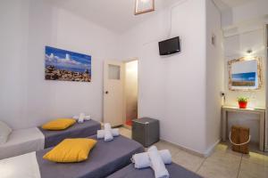 two beds in a room with a couch and a tv at Orpheas Rooms in Mikonos