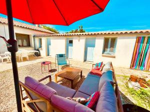 a patio with a couch and a red umbrella at Un air de famille in Saint-Pierre-dʼOléron +8 photos