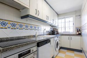 a kitchen with white cabinets and a washer and dryer at Apartment sal y sol in Salobreña