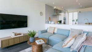 un salon avec un canapé bleu et une télévision dans l'établissement 3 Beach Terrace, à Rhosneigr