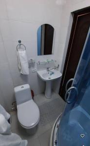 Un baño con un inodoro blanco y un lavabo. en Kungrad, en Qŭnghirot