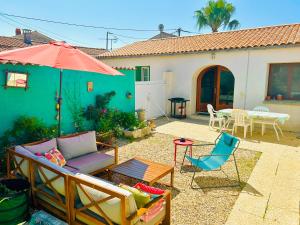 a patio with a couch and an umbrella and a table at Un air de famille in Saint-Pierre-dʼOléron