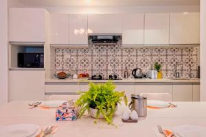 a white kitchen with a table with plates on it at Brand New Luxury 1BHK Apartment by tisyastays in Candolim