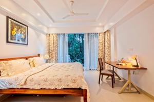 a bedroom with a bed and a desk and a window at Brand New Luxury 1BHK Apartment by tisyastays in Candolim