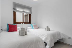 two beds with white sheets and colorful pillows in a room at 2 Bed Apartment in Benahavis Village in Benahavís