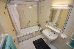 a bathroom with a tub and a sink and a shower at Apartamento Casa do Mar Praia da Luz in Luz +30 photos