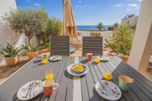a wooden table with plates of food and orange juice at Apartamento Casa do Mar Praia da Luz in Luz
