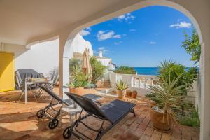a patio with chairs and a table and the ocean at Apartamento Casa do Mar Praia da Luz in Luz