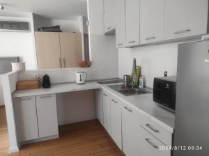 a kitchen with white cabinets and a black microwave at Apartament Nadmorski w Jastarni in Jastarnia +3 photos