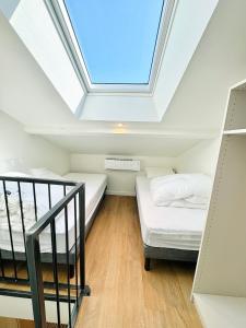 een slaapkamer op zolder met 2 bedden en een dakraam bij Les saisonniers in Grimaud