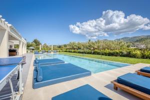 ein Pool mit blauen Liegestühlen und ein Haus in der Unterkunft Villa Serenissima by PosarelliVillas in Acharavi