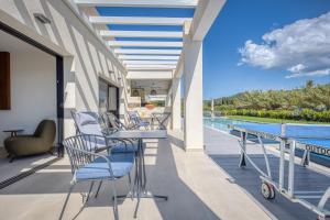 einen Balkon mit Stühlen, einem Tisch und einem Pool in der Unterkunft Villa Serenissima by PosarelliVillas in Acharavi