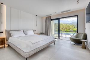ein Schlafzimmer mit einem großen Bett und einem Stuhl in der Unterkunft Villa Serenissima by PosarelliVillas in Acharavi + 46 Fotos
