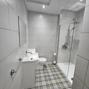 a white bathroom with a sink and a shower at Beach Court Holiday Apartments in Skegness +46 photos