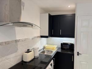 a kitchen with black cabinets and a sink at Hawthorne Barn in Lingwood
